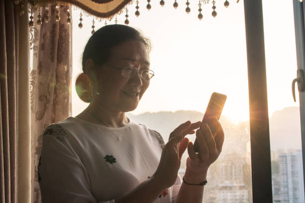 istock Senior Women using mobile phone by window 1145223980