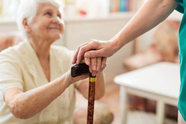 杖に傾いた先輩の手を握る女性のクローズアップ - human hand aging process senior adult cane ストックフォトと画像