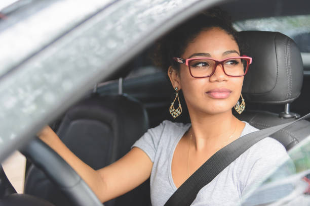 portrait of young woman driving a car - car test drive car rental women imagens e fotografias de stock