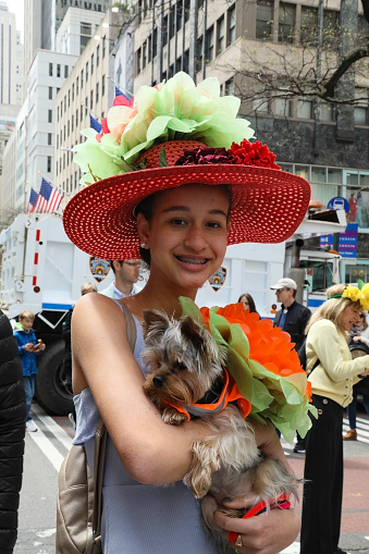 New York City, NY, USA- April 21, 2019: A woman in a decorated Easter Bonnet, holds her dog in a matching costume, during the annual Easter Bonnet Parade on Fifth Avenue.