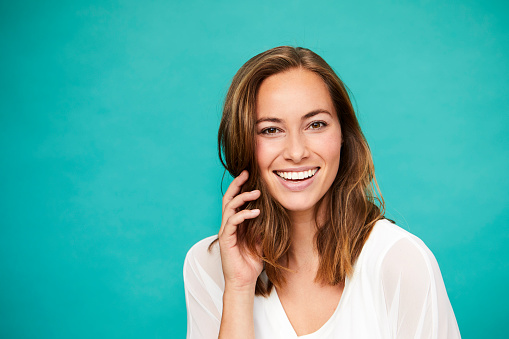 Smiling brunette in white top in blue studio