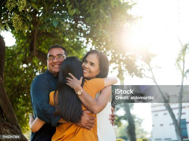 Latin Young Woman Hugging Her Parents Stock Photo - Download Image Now - Family, Latin American and Hispanic Ethnicity, Sunlight