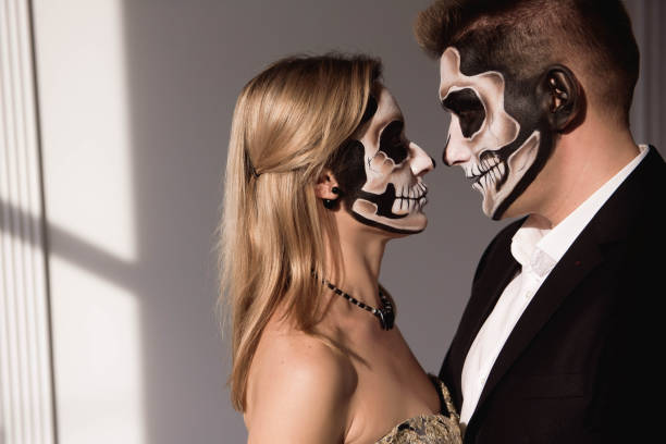 istock Couple with dark skull makeup on white background. Halloween 1145241561