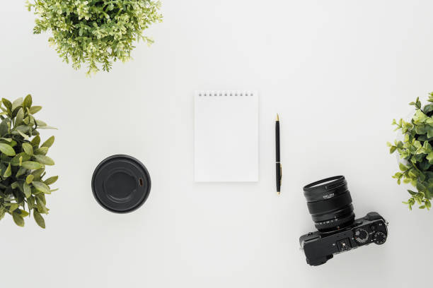 istock Mocap work photographer on a white table. Flat lay mirrorless camera, a few lenses and a notebook with a pen. 1145249071