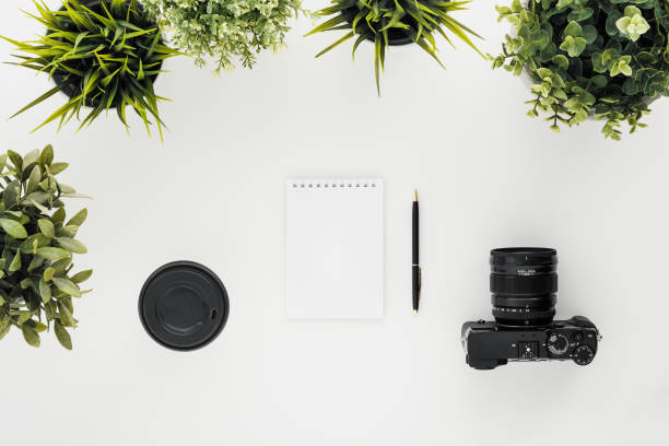 istock Mocap work photographer on a white table. Flat lay mirrorless camera, a few lenses and a notebook with a pen. 1145249084
