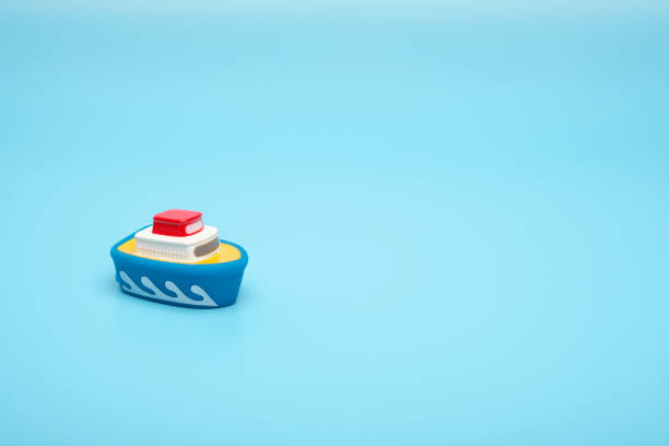 close up little rubber toy boat on a blue background with copy space. - bath toy imagens e fotografias de stock