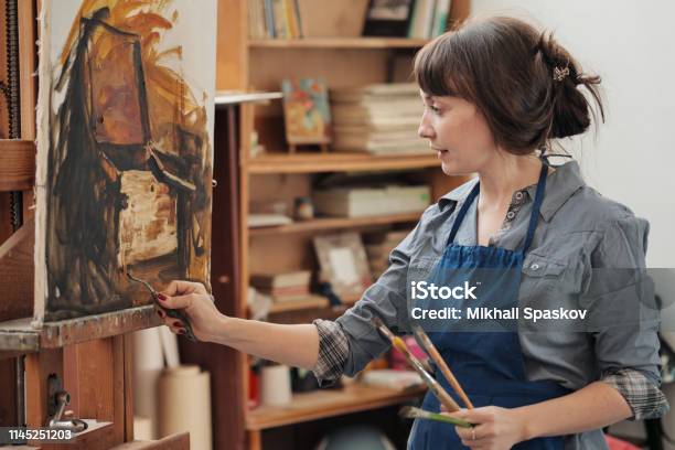 Young Beautiful Woman Painter Among Easels And Canvases In A Bright Studio Stock Photo - Download Image Now