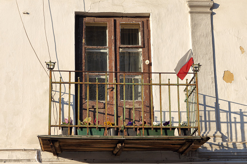 Kazimierz Dolny, Poland - April 15, 2019: Quiant, weathered balcony of an old building with a small Polish flag attached to its railing in anticipation of the National Day in Poland.