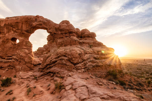 istock The sun breaking the horizon behind a naturally formed sandstone arch causing a star burst effect. 1145263431