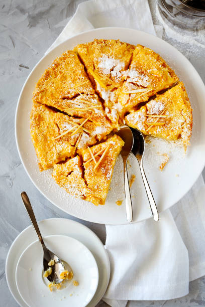 istock Traditional English lemon pudding cake with lemon twist and powdered sugar on a white plate on a light background top view. Homemade fruit pastries for the holiday dinner table 1145265838