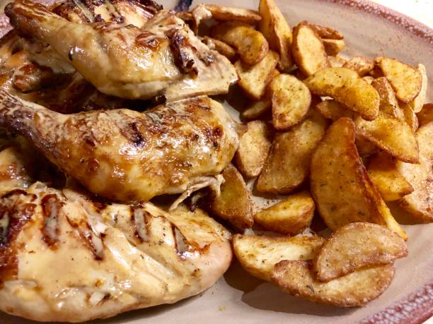 imagen de pechuga de pollo marinada peri peri, muslos y piernas, pollo asado con cuñas de patata picante foto en plato de cena ovalada rosa - roast chicken barbecue chicken french fries chicken fotografías e imágenes de stock