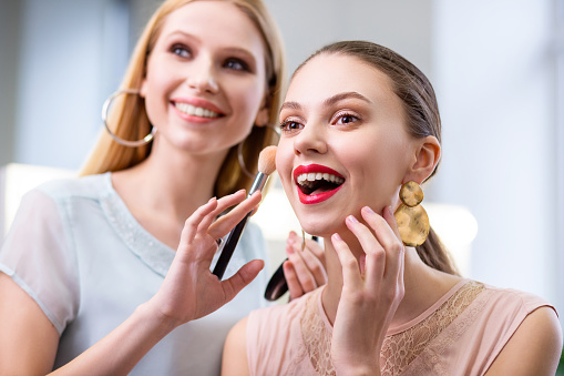 I am so pretty. Joyful nice woman touching her cheek while feeling excited about her makeup