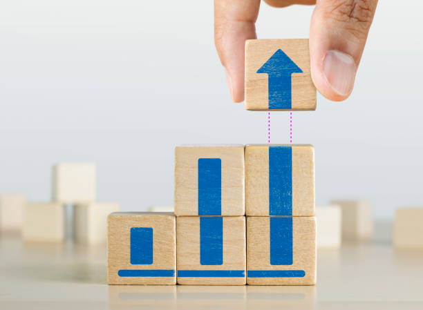 istock Business growth, progress or success concept. Wooden blocks with a growing bar chart graphic arranged in stair shape and a man is holding the top one. 1145270168