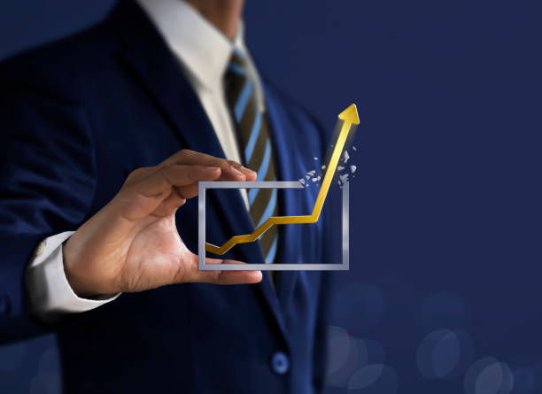 Business growth, progress or success concept. Businessman is holding a growing graph on dark tone background. stock photo