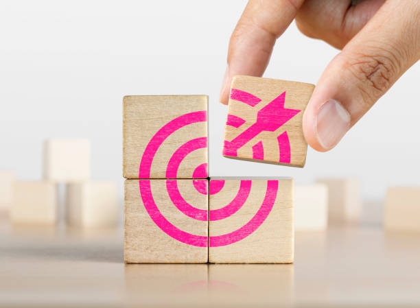 Hand putting the last piece of wooden blocks with the dart target icon. Goal, business goal, achieving a goal or success concept. stock photo