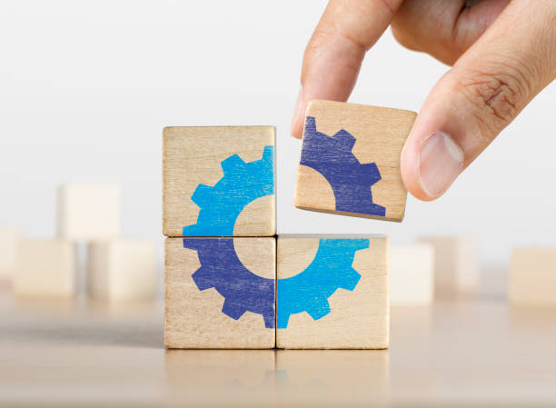 Hand putting the last piece of wooden blocks with the gear icon. Team work, unity, partnership or integration concept. stock photo