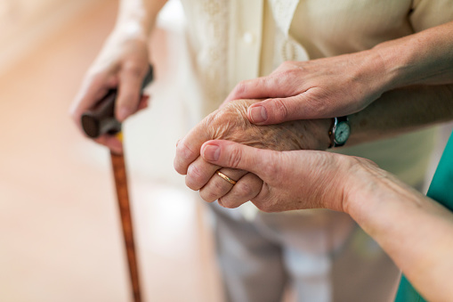 Enfermera consolando a su anciano paciente sosteniendo sus manos photo