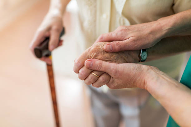 Nurse consoling her elderly patient by holding her hands stock photo