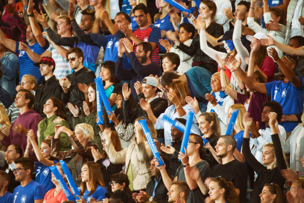 Spectators clapping on a stadium Large number of spectators on a match clapping, smiling and cheering for the blue team. football fans in stadium stock pictures, royalty-free photos & images