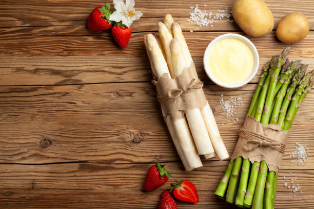 Fresh green and white asparagus with strawberries on rustic wooden table background