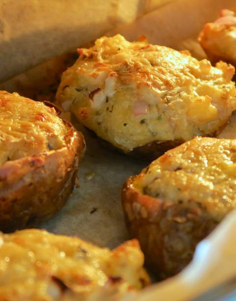 istock Image of stuffed jacket potatoes halves cooking under grill on oven tray, stuffed with mashed baked potato, cheese, onion and herb mixture 1145277705