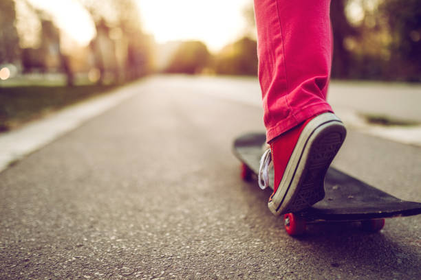 Close up of young urban woman skateboarding downtown, low section