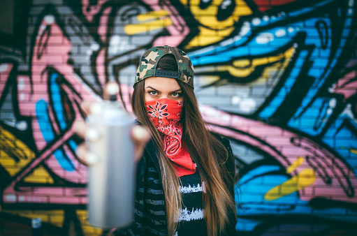 Young woman with bandana is holding aerosol can of spray paint