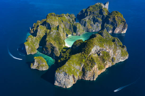 vista de cima, vista aérea deslumbrante de koh phi phi leh (ilhas phi phi) com a bela baía maya. uma água turquesa e clara banhe uma praia branca cercada por montanha de calcário. - maya bay - fotografias e filmes do acervo