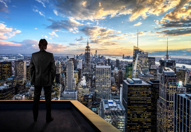 geschäftsmann beobachtet new york city auf dem dach des wolkenkratzers - roof men business city stock-fotos und bilder