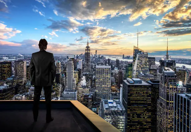 Photo of Businessman watching the New York City on the rooftop of skyscraper