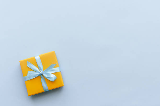 подарочная коробка с лентой на синем фоне на день рождения, день женщин или матерей - yellow box стоковые фото и изображения