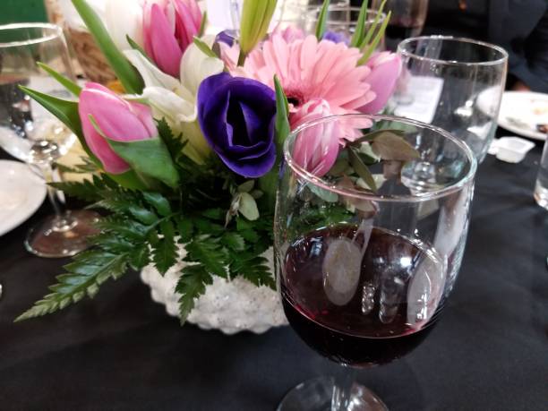 istock Festive dinner table with red wine glass in foreground and flower arrangement and empty wine glasses in background 1145286473