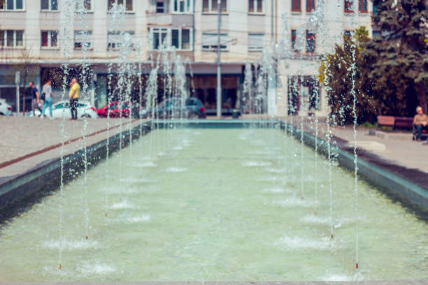 Spray fountain with cool and light blue splashing water stream - Refreshing and relaxing way on a hot summer day in an urban environment