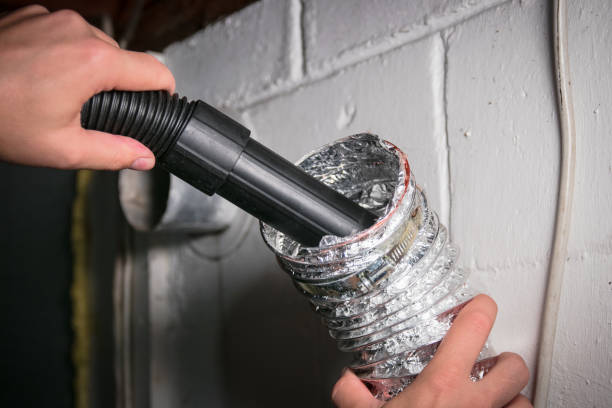 Vacuum cleaning a flexible aluminum dryer vent hose, to remove lint and prevent fire hazard. stock photo