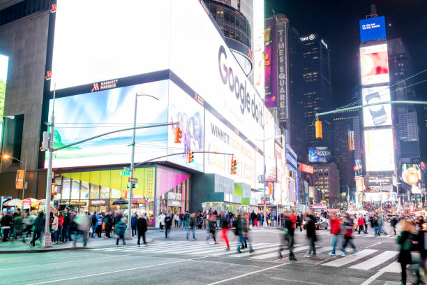 large group of pedestrians crossing street at night, times square, new york city - new york city times square crowd people imagens e fotografias de stock