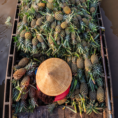 Vietnamese woman selling pineapples on floating market, Mekong River Delta, Vietnam