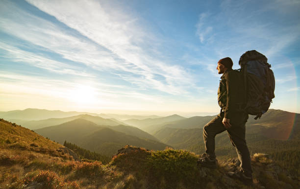 istock The man standing with a camping backpack on the rock with a picturesque sunrise 1145301828