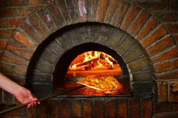 istock Pizza maker with pizza from the stone stove 1145302169