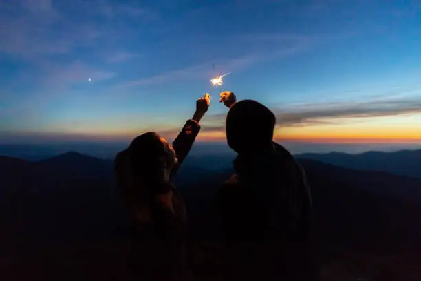 Photo of The man and a woman hold firework sticks. evening night time