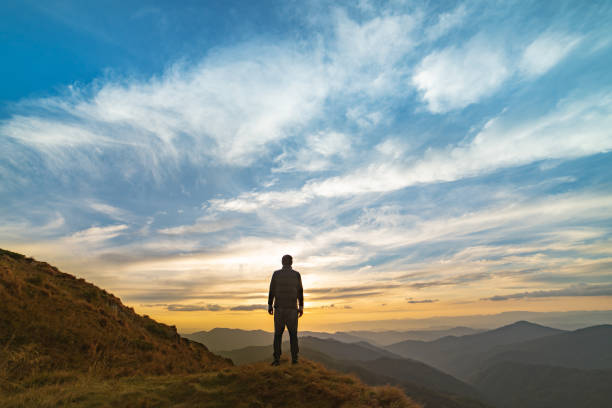 człowiek stojący na skale z malowniczym zachodem słońca - mountain peak mountain snow hiking zdjęcia i obrazy z banku zdjęć