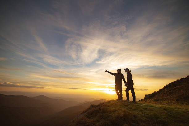 le couple gestes sur la roche avec un coucher de soleil pittoresque - mountain rock sun european alps photos et images de collection