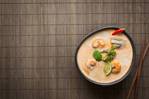 tom yam kung soupe thaï épicée avec crevettes, fruits de mer, lait de coco, piment sur mat. - thailand thai cuisine prawn tom yum soup photos et images de collection
