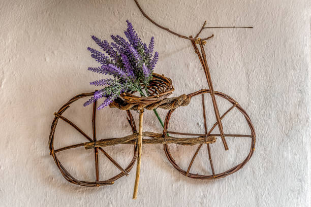 istock Purple wildflower on small bicycle ornament handmade using thin tree branches hanging on an old wall 1145304902