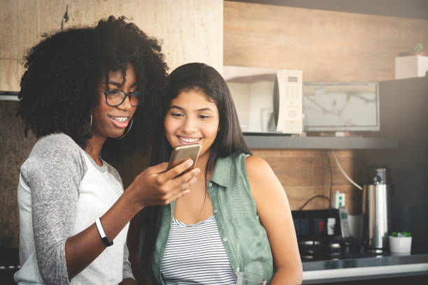 istock Two girls, looking at cell phone and smiling 1145315308