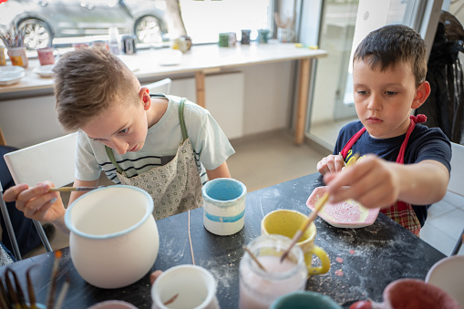 Caucasian Boys Painting Pottery