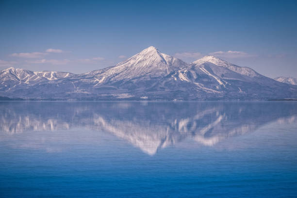 Stunning tall mountain peak and fir trees reflecting in clear alpine lake