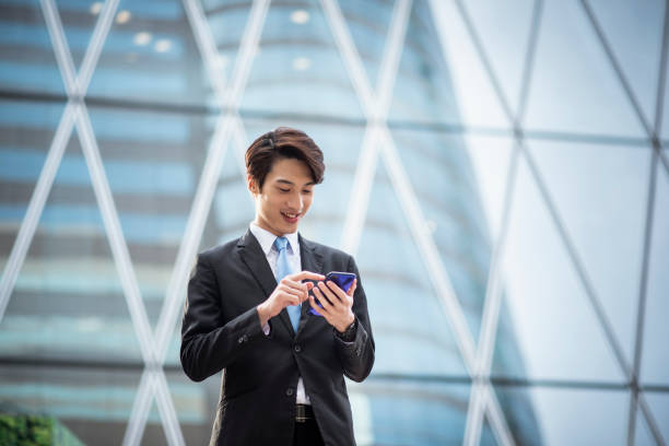 istock Chinese businessman using a smart phone in front of an office building 1145350470