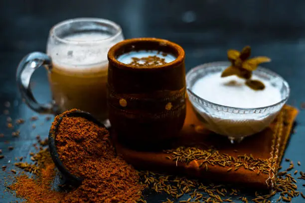 Photo of Traditional summer drink i.e. is most popular in Asia and India i.e. Chas or chaas or buttermilk or chhaachh in a clay glass with curd and coriander powder and salt on wooden surface,Close up.