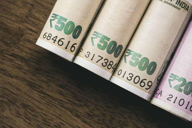 istock Rolls of Indian rupee money banknote on wood background 1145351421