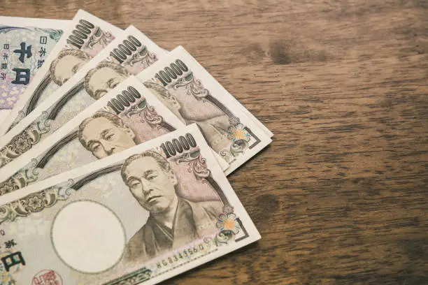 Ten thousand Japanese Yen banknotes on wood table with copy space for financial concept